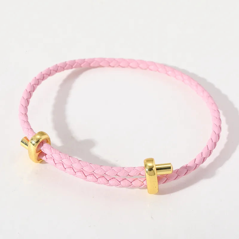 Rosafarbenes geflochtenes Lederarmband mit goldfarbenen Details.