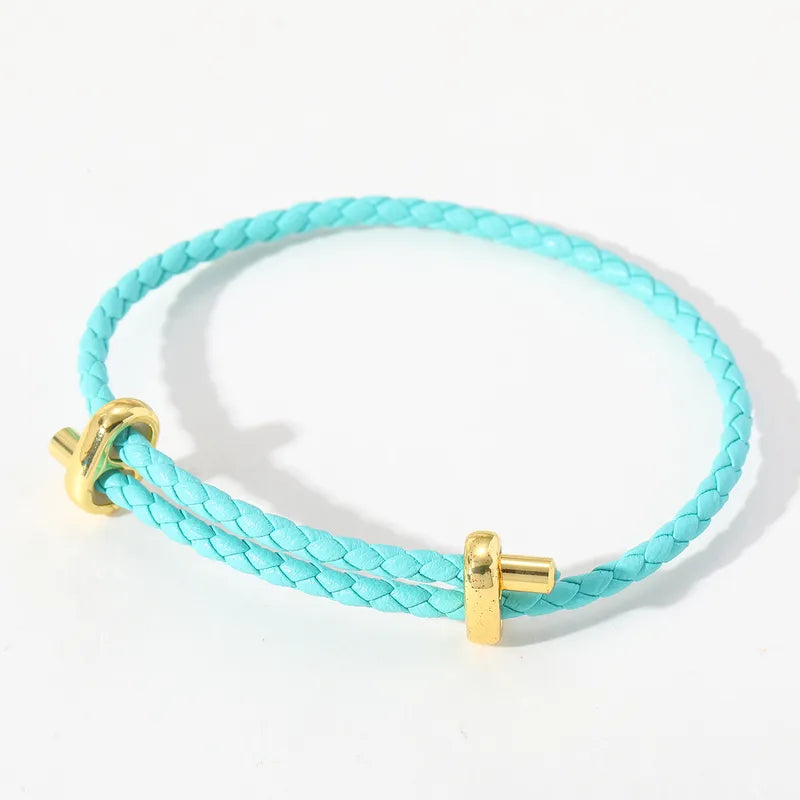 Türkisfarbenes geflochtenes Lederarmband mit goldfarbenen Details.