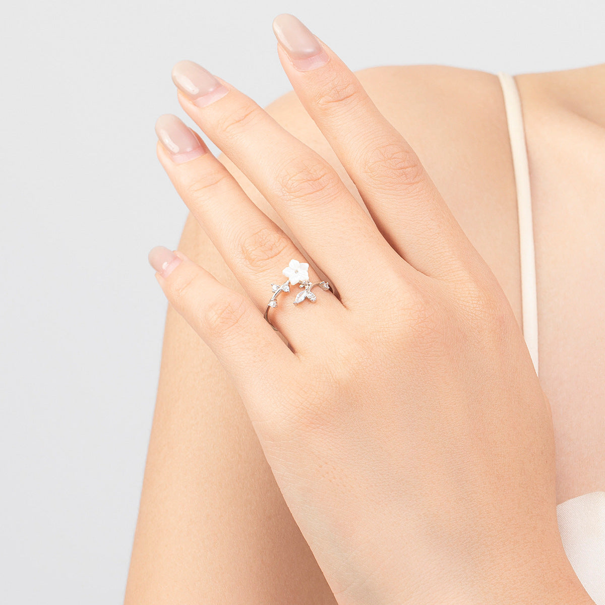 Zarter floraler Damenring aus 925 Silber mit Perlmuttblume – offen und elegant am Finger getragen.