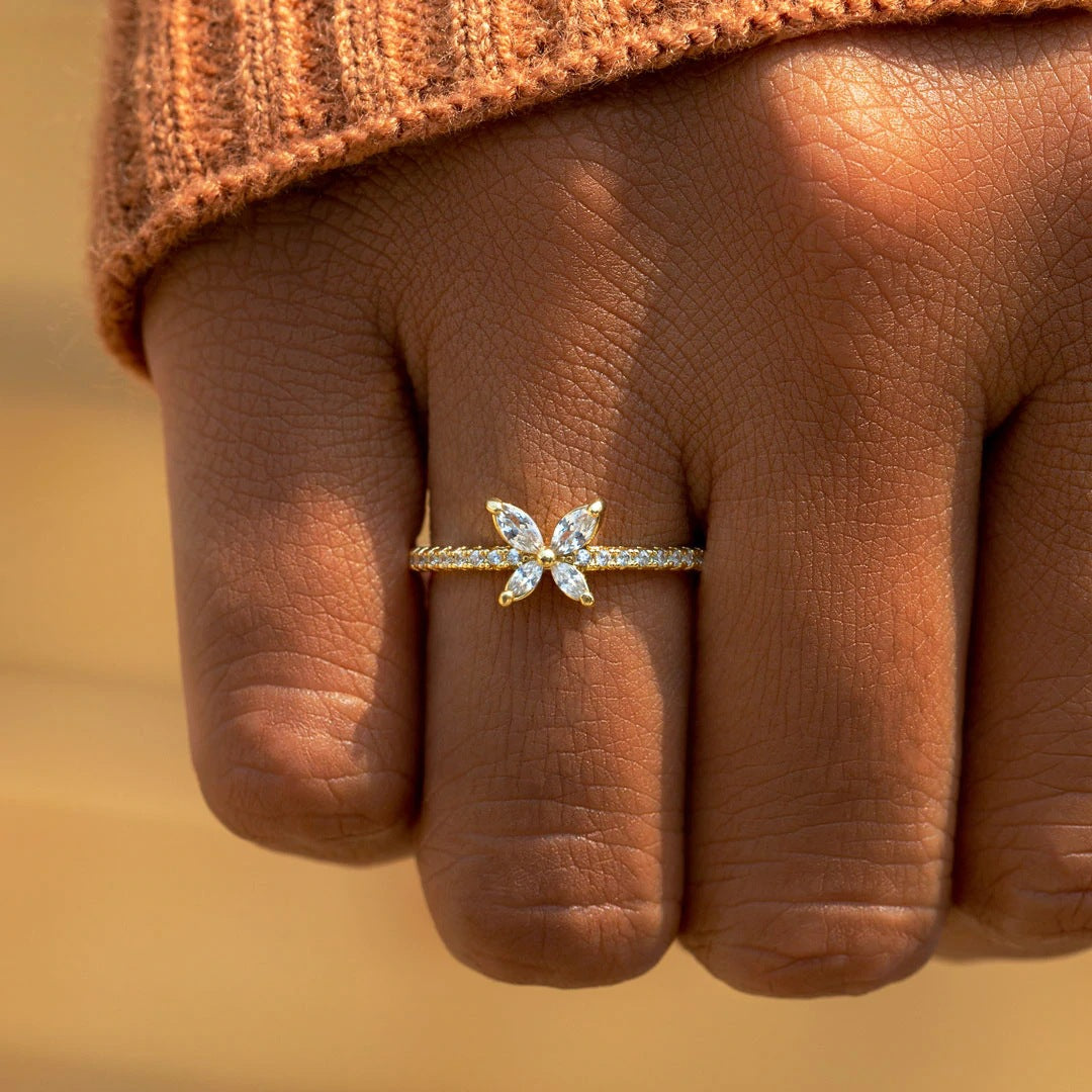 Vergoldeter Silberring mit Zirkonia in Schmetterlingsform an einem Finger getragen, Nahaufnahme bei Tageslicht.