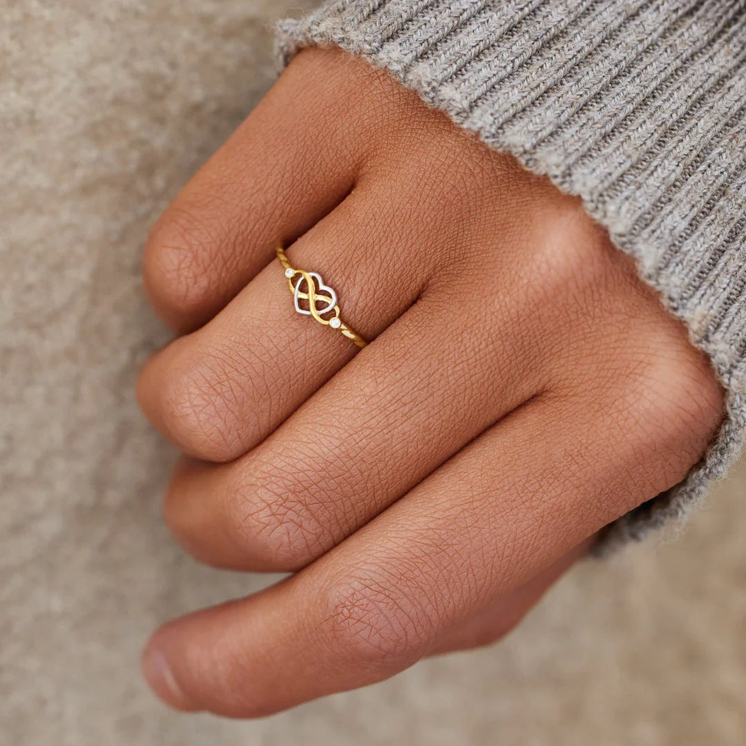 Zarter Ring mit Herz und Unendlichkeitszeichen an der Hand getragen – fein, emotional und elegant.