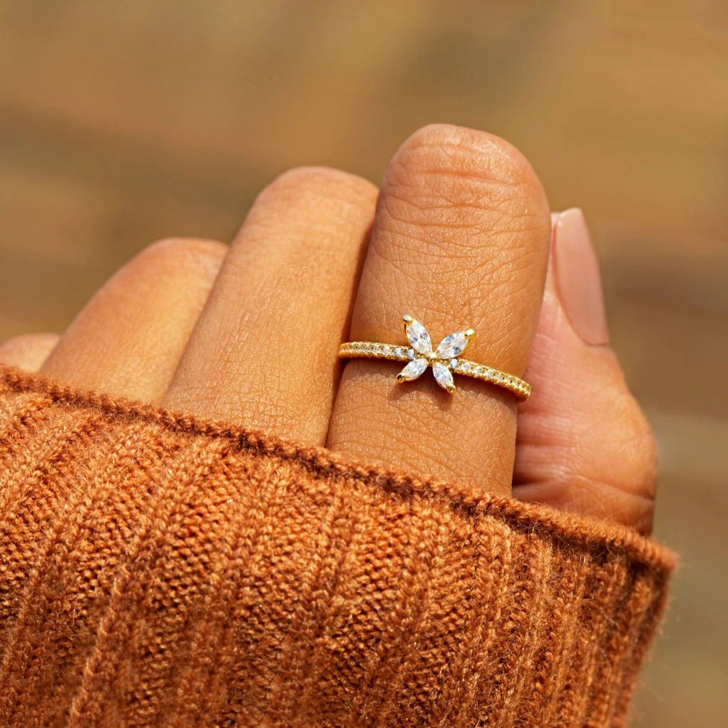 Schmetterlingsring aus vergoldetem 925er Silber mit Zirkonia, getragen an der Hand, kombiniert mit herbstlicher Kleidung.